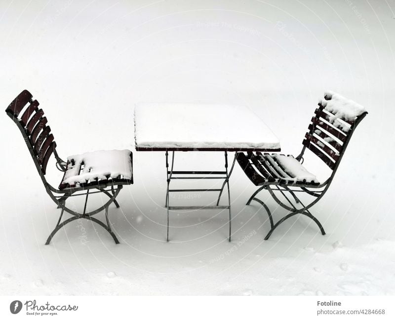 Ein lauschiges Plätzchen im Schnee. 2 eingeschneite Stühle und ein Tisch warten auf Gäste, die eine kleine Abkühlung brauchen. Winter Licht kalt weiß Eis Frost