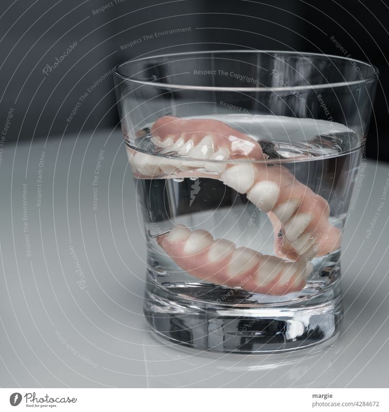 Zahnersatz (Gebiss) in einem Wasserglas Zahnmedizin Gesundheit Zähne Mund Pflege Nahaufnahme Labor zahngesundheit senioren altern skuril Künstliche zähne
