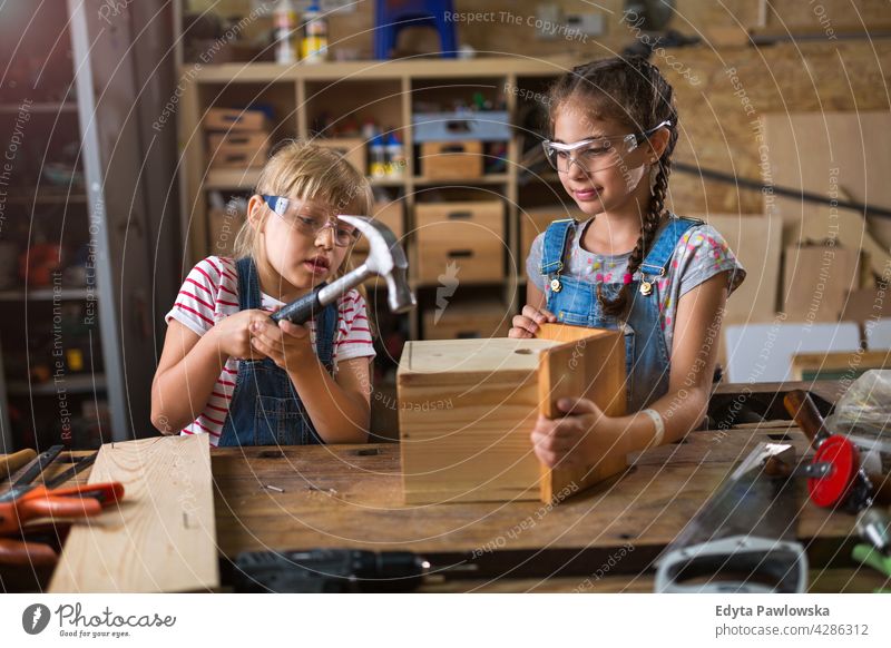 Zwei kleine Mädchen bauen Vogelhaus in der Garage Werkstatt arbeiten Menschen Kind Kinder Frauenpower Fähigkeit Handwerk Hobby Lifestyle Werkzeuge Konzentration