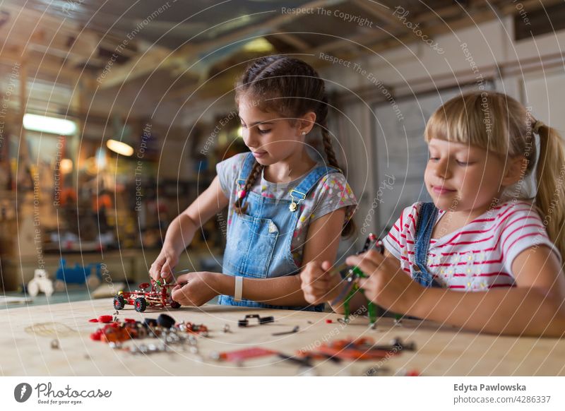 Kleine Mädchen bauen Spielzeug Baumaschine Werkstatt Lernen Menschen Kind Kinder Frauenpower Fähigkeit Handwerk Garage Hobby Lifestyle Werkzeuge Konzentration
