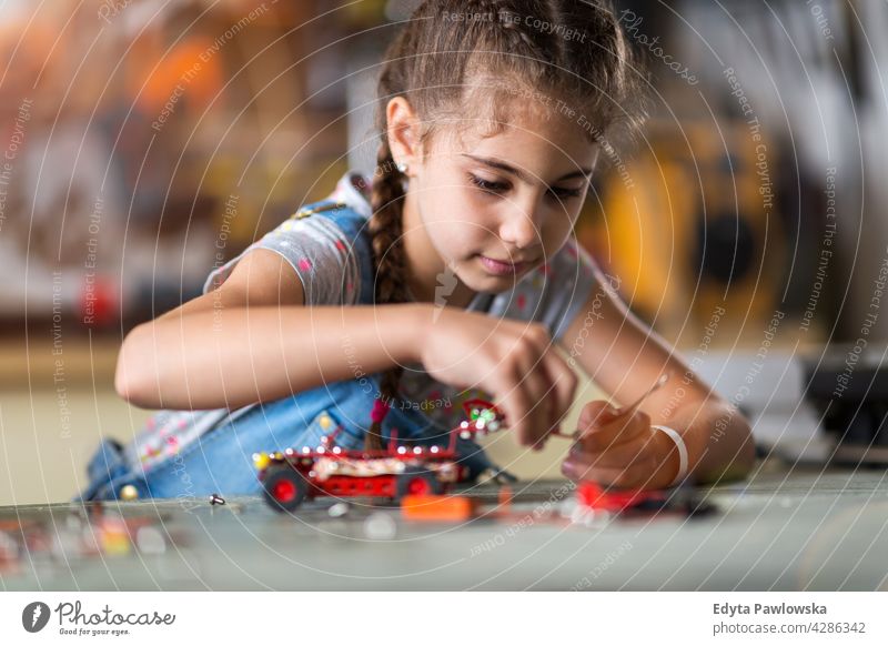 Kleines Mädchen baut einen Roboter Werkstatt Lernen Menschen Kind Kinder Frauenpower Fähigkeit Handwerk Garage Hobby Lifestyle Werkzeuge Konzentration