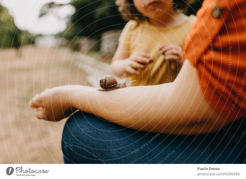 Kind betrachtet Schnecke, die auf dem Arm der Mutter kriecht Riesenglanzschnecke Schneckenhaus Kindheit Kindererziehung Außenaufnahme Tier Natur Farbfoto Tag 1