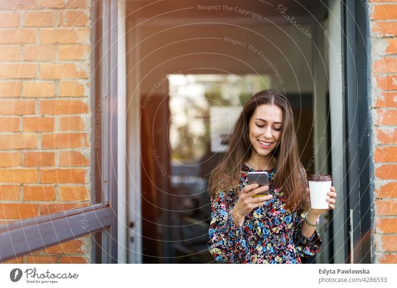 Junge Frau steht vor einem Café urban Straße Großstadt stylisch Kaffee zum Mitnehmen Menschen junger Erwachsener lässig attraktiv Lächeln Glück Kaukasier