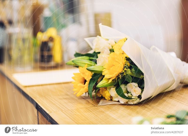 Ein schöner Strauß heller gemischter Blumen liegt auf einem Holztisch, die Arbeit eines Floristen in einem Blumenladen Blumenstrauß Werkstatt Blumenhändler