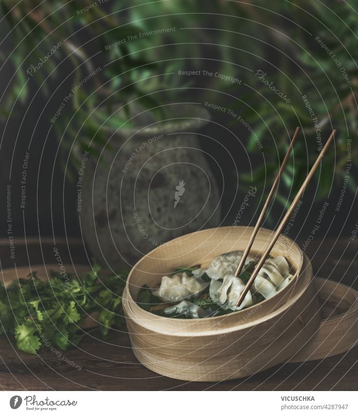 Asiatisches Essensstillleben mit Bambusdampfer und hausgemachten Knödeln auf rustikalem Tisch. Stillleben Vorderansicht Gesundheit gesunde Ernährung frisch