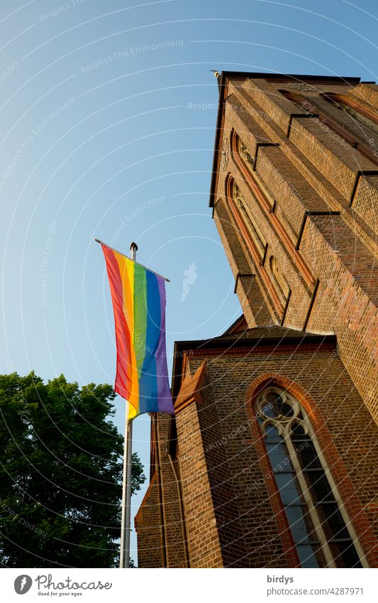 Regenbogenfahne vor einer katholischen Kirche. Solidarität mit gläubigen Homosexuellen entgegen der Vorgabe des Vatikans Homosexuelle nicht zu trauen