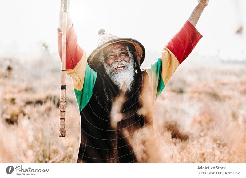 Glücklicher Hippie-Rastamann auf dem Feld stehend Mann rastafarian Lächeln männlich Freude heiter Kultur ethnisch Reggae aufgeregt Karibik Sieg Natur