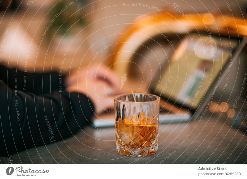 Person, die an einem Laptop mit einem Glas Whiskey arbeitet Mitarbeiter benutzend orange beschäftigt Tippen freiberuflich Internet Gerät Weinbrand Apparatur
