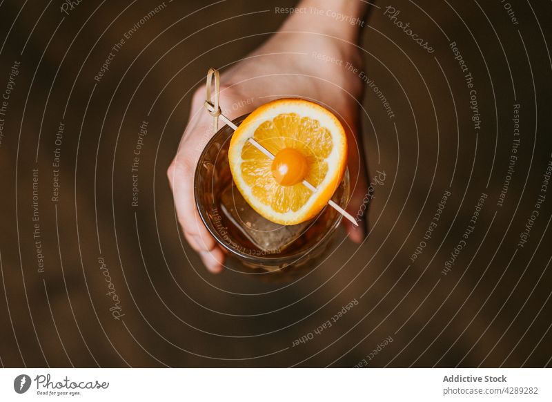 Person mit Whiskey mit Eis und Stück von Orange Alkohol orange Frucht Spielfigur Würfel Beeren kalt durchsichtig cool Kristalle liquide kleben Glaswaren Getränk