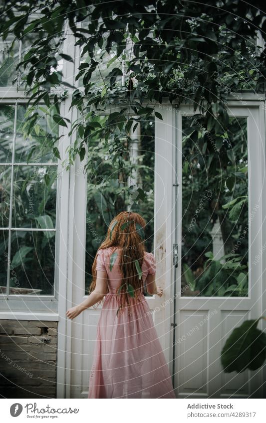 Frau in langem Kleid steht in der Nähe der Tür eines Gewächshauses Pflanze Garten Laubwerk wachsen üppig (Wuchs) Türöffnung vegetieren natürlich Wachstum frisch