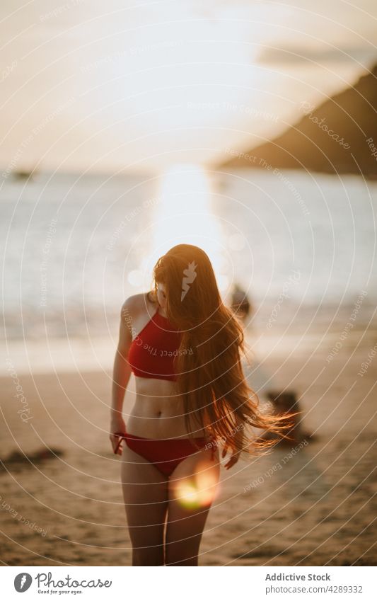 Anonyme Frau in Badehose am Strand Badebekleidung Badeanzug Küste Ufer MEER Erholung tropisch Sommer Meeresufer Freizeit schlank rot Resort Seeküste Sand Wasser