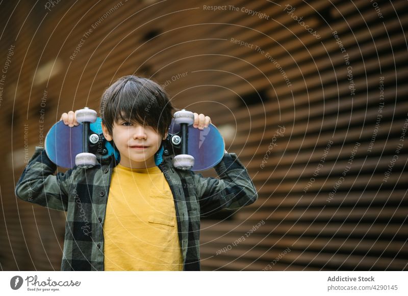 Positiver Junge mit Skateboard auf der Straße Kind Kindheit Hobby sportlich Skateboarderin spielerisch Erholung sorgenfrei lässig Glück Streetstyle Lächeln