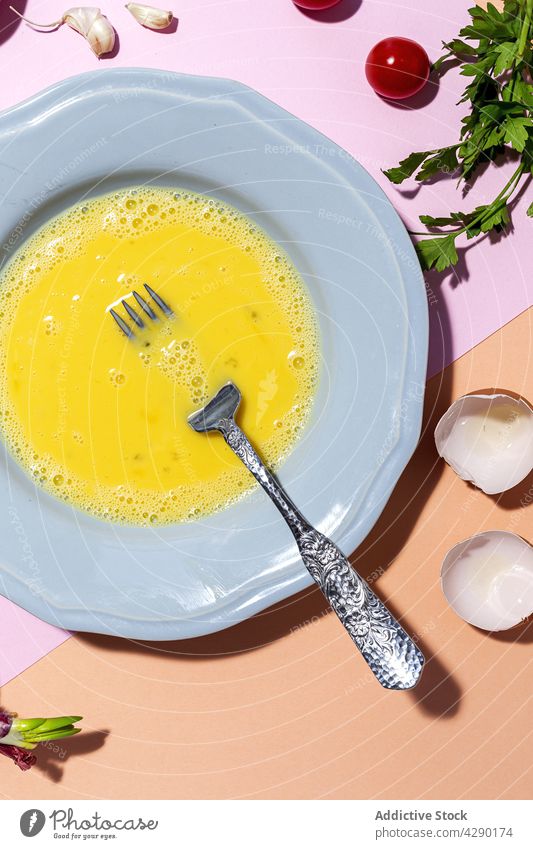 Geschlagenes Ei auf dem Teller gegen reife Petersilie frisch Bestandteil Kirschtomate natürlich organisch Produkt kulinarisch Rezept roh farbenfroh glühen
