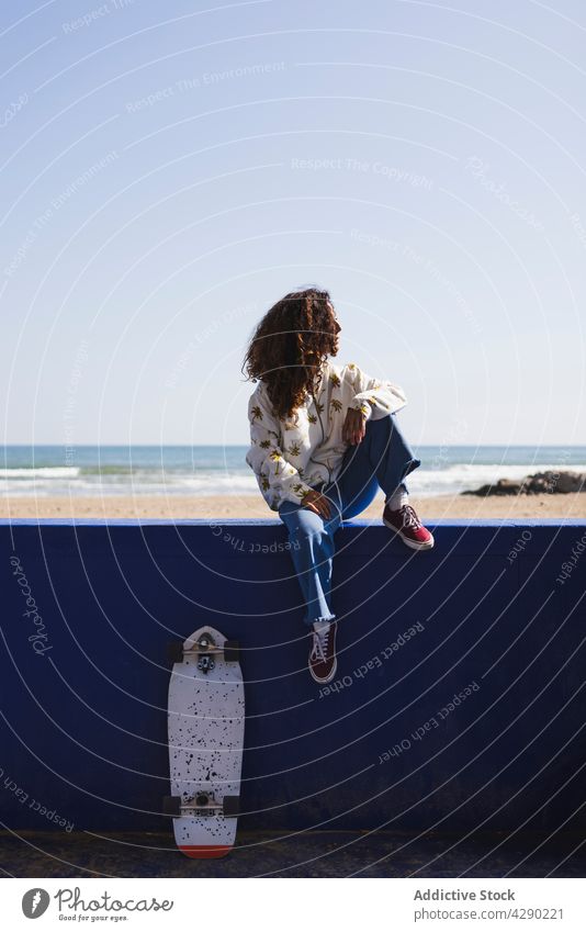 Frau sitzt auf dem Geländer an der Strandpromenade Skateboard Reling Seeküste Meeresufer Hobby Küste sportlich Skateboarderin nachdenklich Hafengebiet Sand Ufer