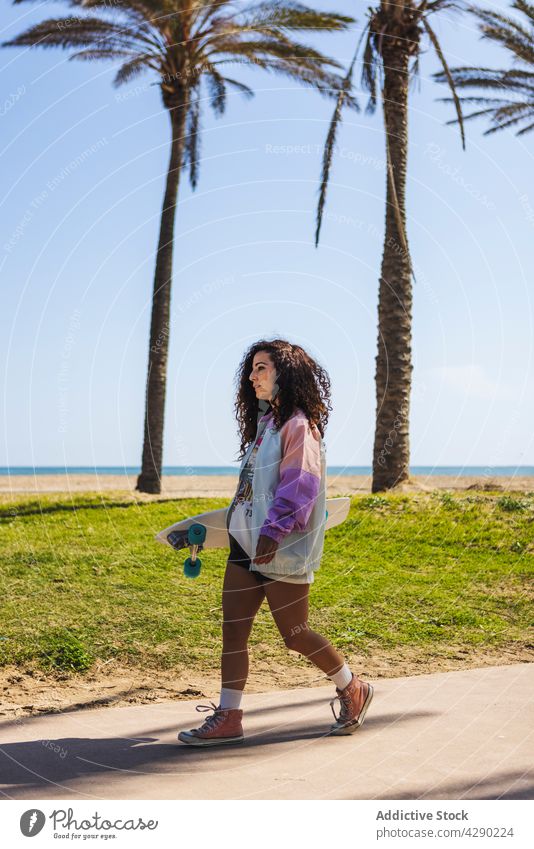 Frau mit Skateboard in der Nähe der Böschung Skateboarderin Hobby Strand Küste Sport Stauanlage Strandpromenade Bürgersteig Longboard lässig sportlich jung