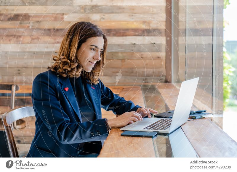 Frau arbeitet per Fernzugriff mit Netbook in einem Café freiberuflich Kantine Tisch modern Stuhl positiv Fenster nachdenklich Erwachsener Laptop selbstbewusst