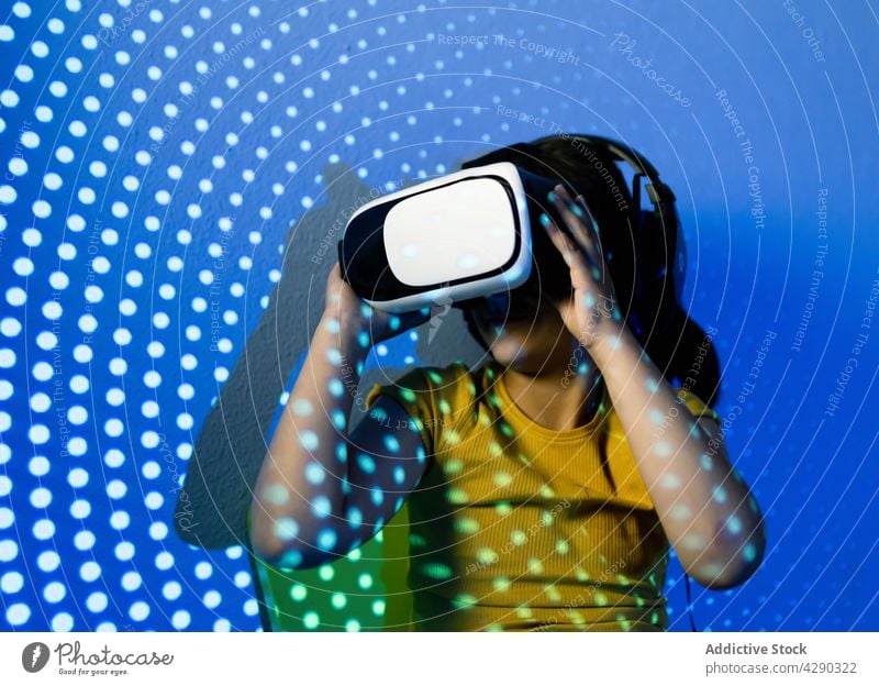 Fröhliches Mädchen mit VR-Brille in Neonlicht Erfahrung Schutzbrille aufgeregt freudig neonfarbig heiter unterhalten Headset expressiv Gerät Spaß Lachen