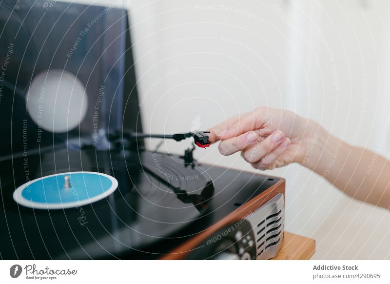Unbekannte Frau, die zu Hause einen Plattenspieler mit einer Schallplatte einschaltet antörnen Spieler Aufzeichnen Vinyl Nostalgie retro Musik heimwärts