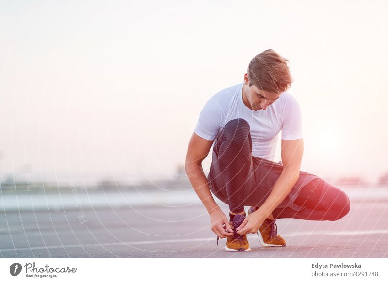 Sportlicher junger Mann auf Parkebene in der Stadt bei Sonnenuntergang Jogger Läufer Joggen rennen Menschen männlich Energie Übung Bekleidung trainiert. Fitness