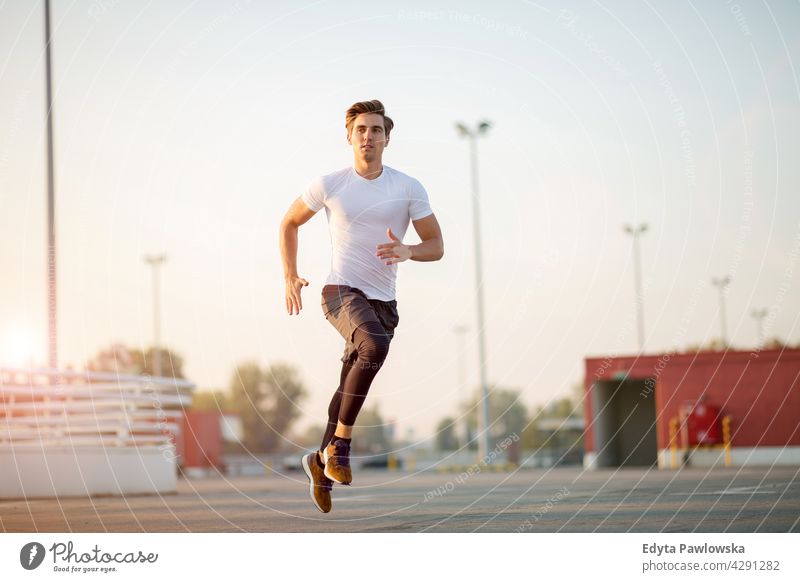 Junger Mann läuft auf Parkebene in der Stadt bei Sonnenuntergang Jogger Läufer Joggen rennen Menschen jung männlich Energie Übung Bekleidung trainiert. Fitness
