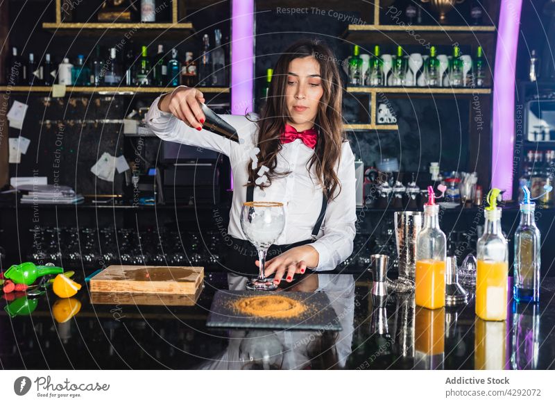Stilvolle Frau bei der Zubereitung eines alkoholischen Cocktails in einer modernen Bar vorbereiten Alkohol trinken Barkeeper Eiswürfel Getränk Schüttler