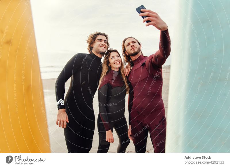 Surferfreunde am Strand mit Surfbrettern machen Selfie mit Handy Sportler Freunde Lächeln Sand Meeresufer Smartphone Aktivität Glück Lifestyle Wasser