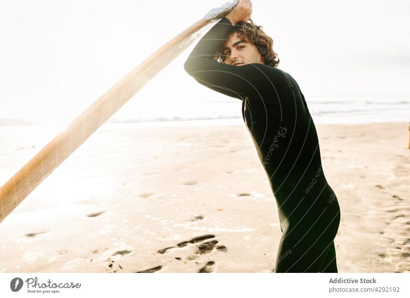 Surfer stehend am Strand mit Surfbrett Mann Natur Sonnenuntergang Lächeln winken im Freien Neoprenanzug Meeresküste männlich Brandung Sportler MEER Glück Surfen