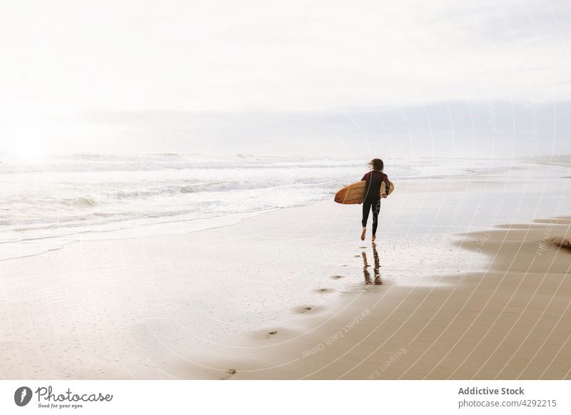 Anonymer Surfer am Strand mit Surfbrett Mann Natur laufen Sonnenuntergang winken im Freien Neoprenanzug Meeresküste männlich Brandung Sportler MEER Surfen Hobby