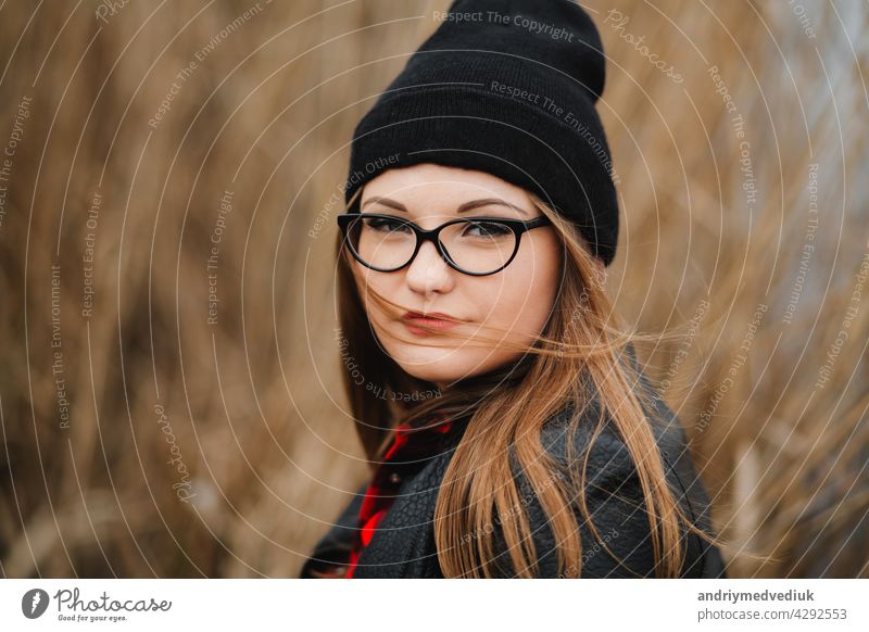 Porträt eines schönen jungen Mädchens in der Nähe des Sees im Schilf in einer dunklen Lederjacke und Brille Herbst Röhricht Park Frau Lächeln Landkarte