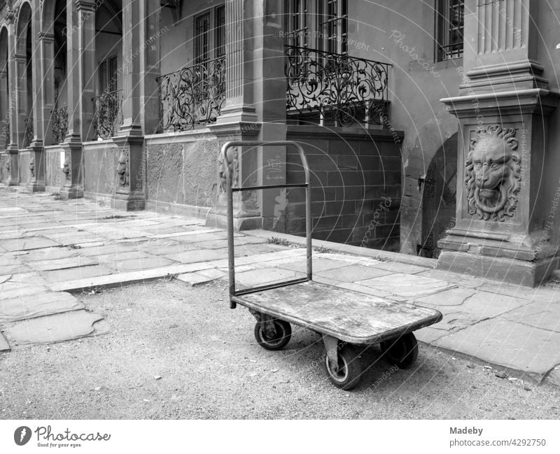 Alter Plattformwagen im Hof des Isenburger Schloss mit alter Renaissance Fassade in Offenbach am Main in Hessen, fotografiert in neorealistischem Schwarzweiß