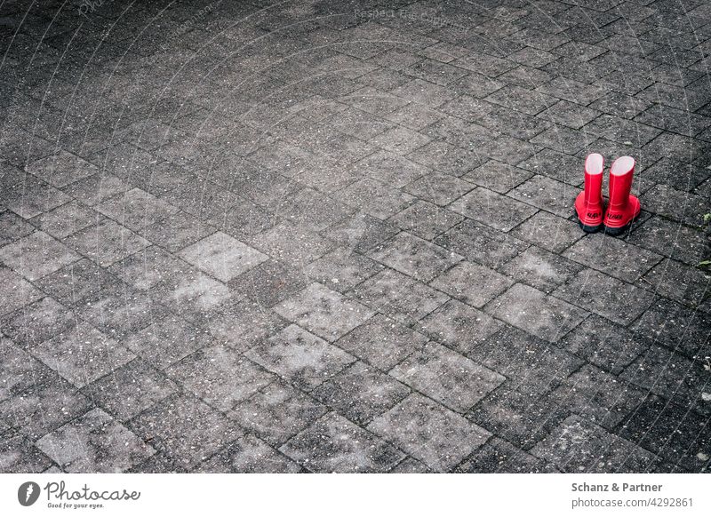 rote Gummistiefel auf Steinboden Pflastersteine Kindershuhe spielen Füße draußen versiegelt grau Außenaufnahme Farbfoto Menschenleer Straße Wege & Pfade