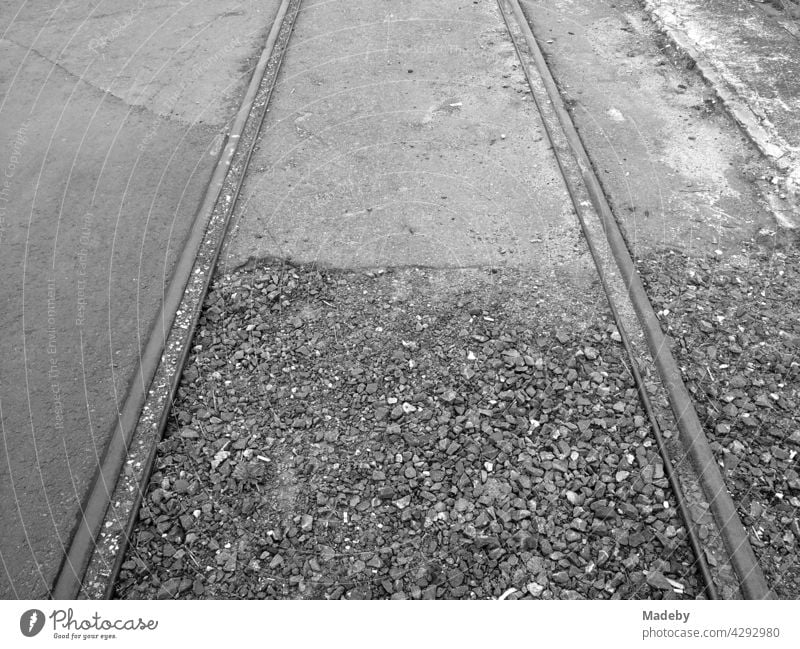Alte Schienen in Schotter und Asphalt oder ehemaligen Hafenbahn am alten Binnenhafen in Offenbach am Main in Hessen, fotografiert in klassischem Schwarzweiß