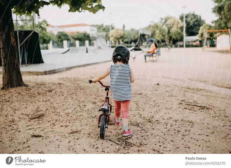 Rückansicht Mädchen mit Fahrrad Kind 1-3 Jahre Park authentisch Mensch Farbfoto Kleinkind Außenaufnahme Kindheit Tag Glück Lifestyle Fröhlichkeit mehrfarbig