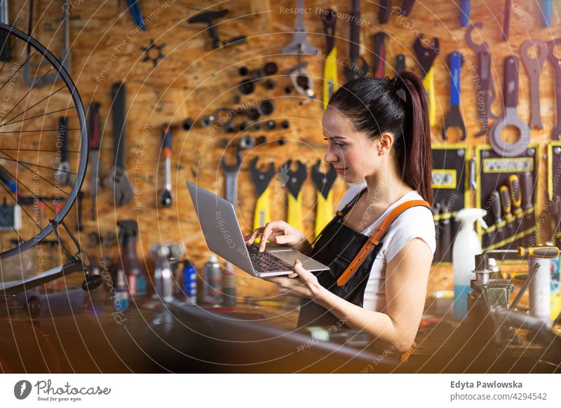 Frau mit Laptop in einer Fahrradwerkstatt Handelsvertreter Fahrradmechaniker Fahrradfahren Fahrradladen Business Einzelhandel Zyklus hilfreich im Innenbereich