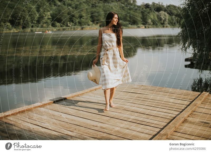 Entspannende junge Frau steht auf Holzsteg am See schön Konzept genießen Sommer Pier Natur Kaukasier gut lässig sonnig träumen Person Urlaub Freizeit ruhen