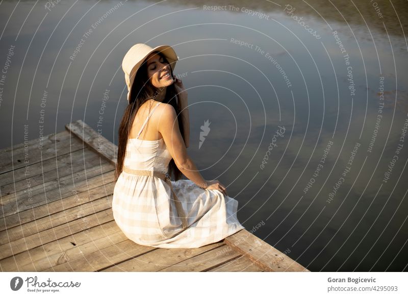 Entspannende junge Frau auf Holzsteg am See schön Konzept genießen Sommer Pier Natur Kaukasier gut lässig sonnig träumen Person Urlaub Freizeit ruhen sorgenfrei