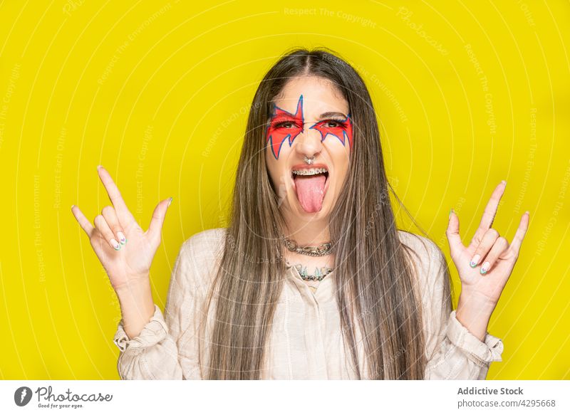Frau gestikuliert mit Felszeichen und zeigt Zunge Rock and Roll Zunge zeigen gestikulieren kreativ Make-up Hupe Stil farbenfroh hell jung Felsen Musik Mode