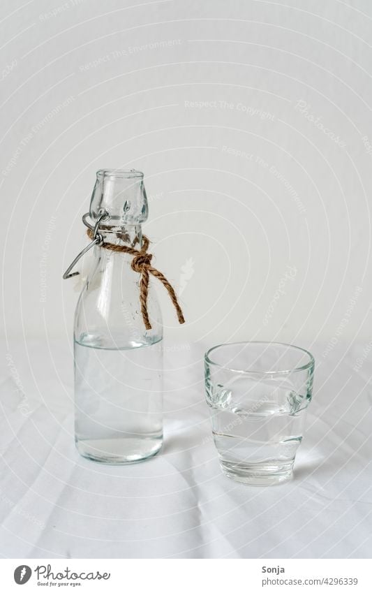 Glasflasche und ein Trinkglas mit Wasser auf einem weißen Tischtuch tischtuch trinken Getränk Erfrischungsgetränk Flasche Trinkwasser Gesundheit kalt Sommer