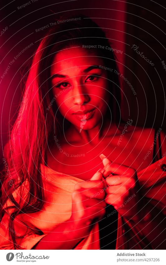 Junge attraktive hispanische Frau auf der Terrasse bei Nacht ruhen neonfarbig Rotlicht Stil dunkel jung leuchten sich[Akk] entspannen Freude ethnisch positiv