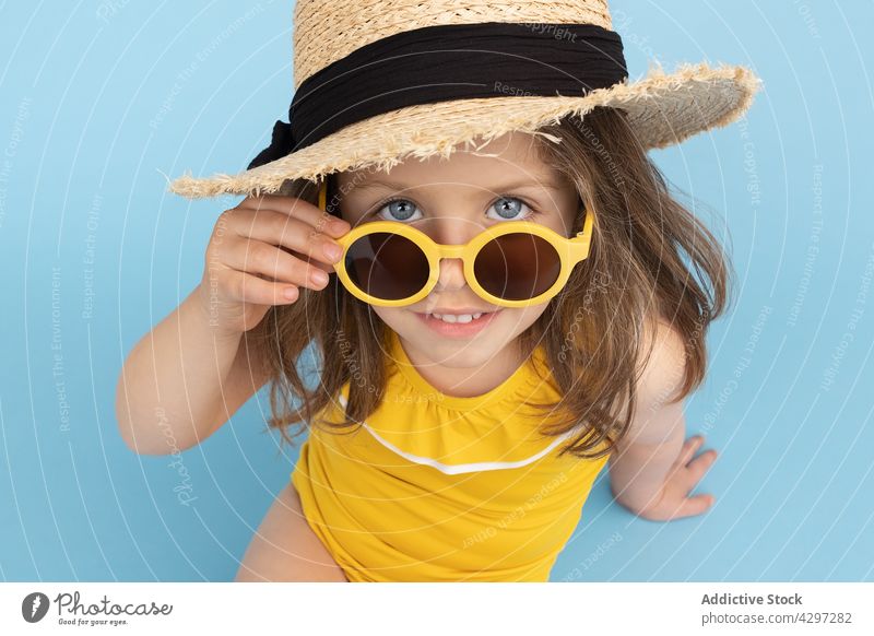 Stilvolles kleines Mädchen im Sommeroutfit gelb Mode Glück Lächeln Kind Sonnenbrille Strand niedlich wenig hell heiter trendy sorgenfrei Strohhut Farbe Outfit