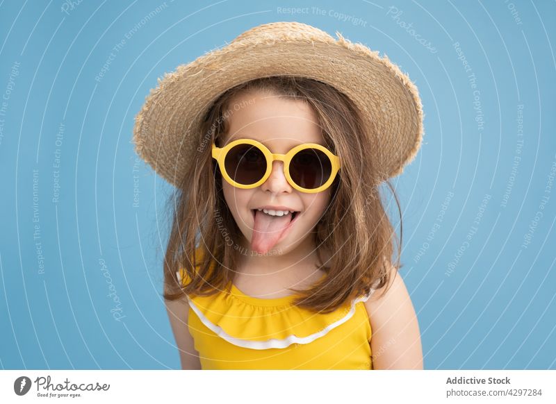 Kleines Mädchen mit gelber Sonnenbrille zeigt Zunge Sommer Stil Mode Zunge zeigen spielerisch Glück Kind Lächeln Strand niedlich wenig Spaß haben hell heiter