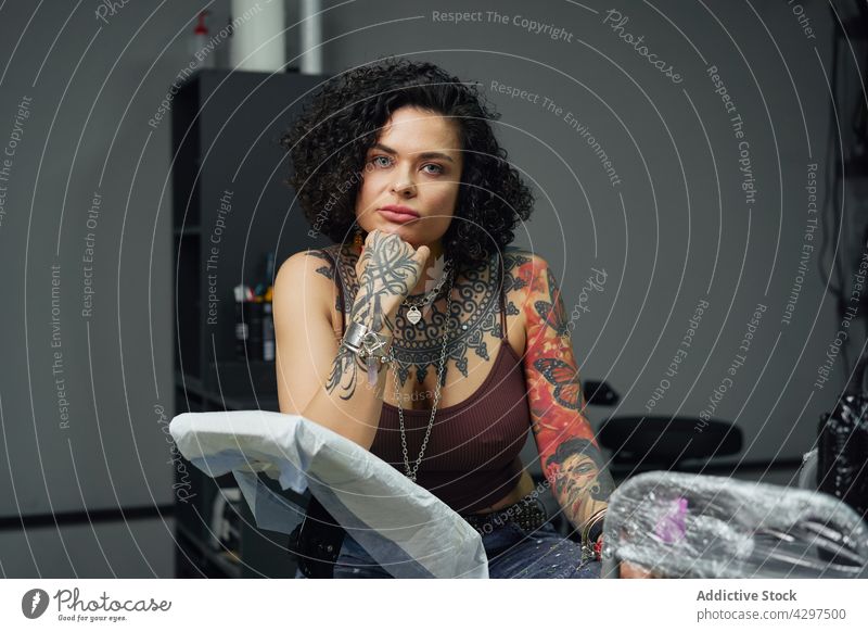 Selbstbewusste Frau mit Tattoos im Tattoo-Studio Atelier selbstbewusst allein informell Salon ernst Accessoire Erwachsener Vorschein Individualität auflehnen