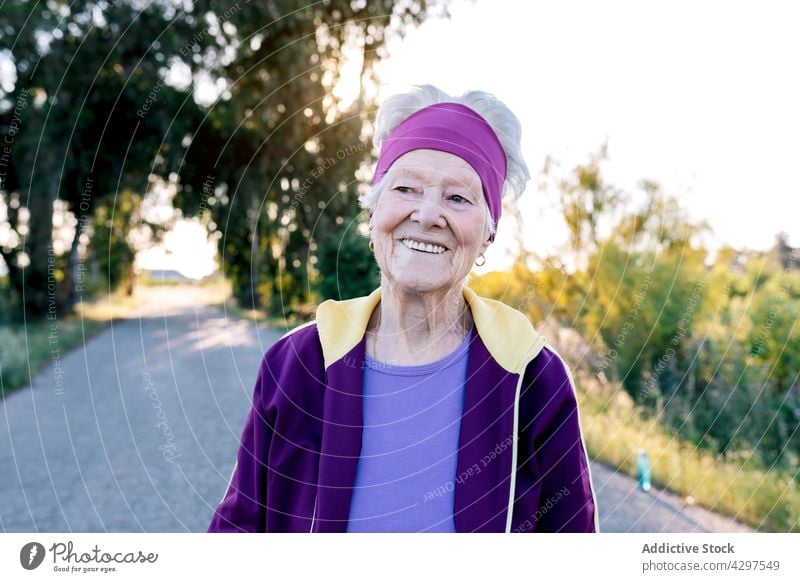 Positive ältere Sportlerin lächelnd und gehend Spaziergang Training Landschaft Fitness Morgen Gesundheit Sommer Straße Lächeln Frau Jogger gealtert Senior Glück