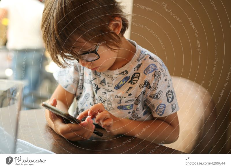 Junge mit Brille und Blick auf ein Display eines Handys Kindererziehung Homeschooling Surfen im Netz Karikaturen anschauen aussruhen Anschluss per Telefon
