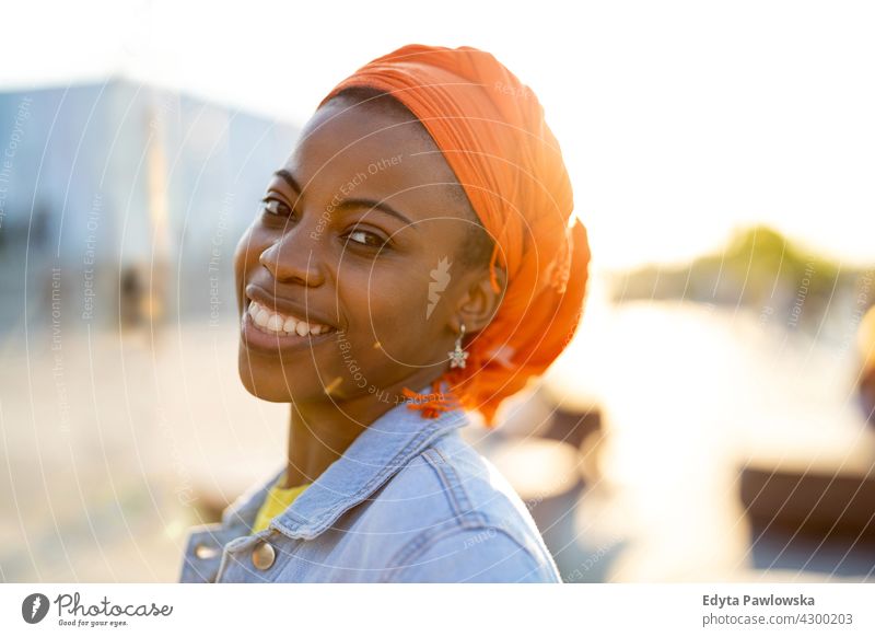 Junge Frau in orange Kopfbedeckung bei Sonnenuntergang Afro-Look stolz echte Menschen Stadtleben Afroamerikaner Afrikanisch Schüler schwarz Ethnizität sonnig