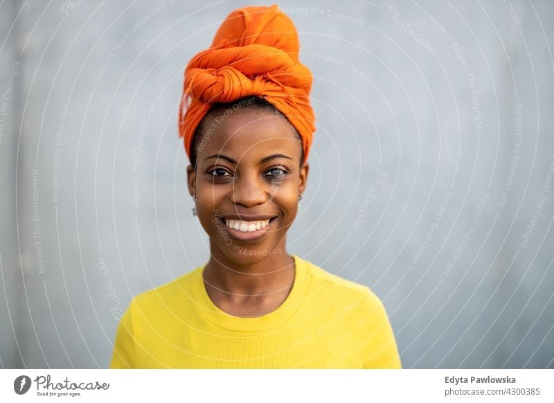 Schöne junge Frau lächelnd vor einer grauen Wand Afro-Look stolz echte Menschen Stadtleben Afroamerikaner Afrikanisch Schüler schwarz Ethnizität sonnig