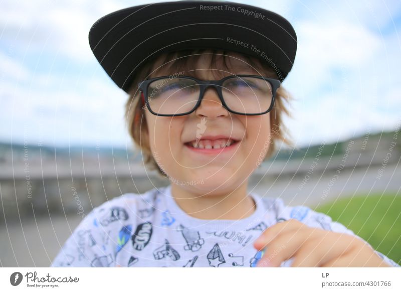 Kind mit Hut und Brille lächelt in die Kamera Stil Design Mensch Gefühle Farbfoto Eltern Kontrast Hintergrund neutral Strukturen & Formen Erholung Sinnesorgane