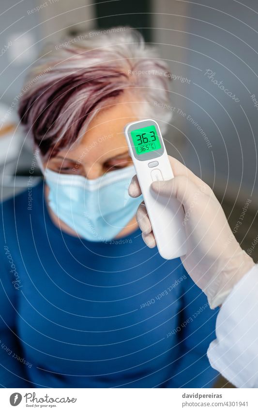 Ältere Frau ohne Fieber, deren Temperatur mit einem Infrarotthermometer gemessen wird Senior kein Fieber Infrarot-Thermometer Arzt Coronavirus Gesundheit