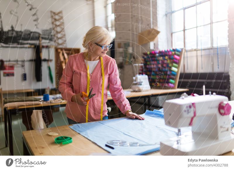 Senior Modedesignerin in ihrem Atelier Nähmaschine Stoff Gewebe Material Nähen Designer Damenschneiderin Näherin Schneider Bekleidung im Innenbereich Frau