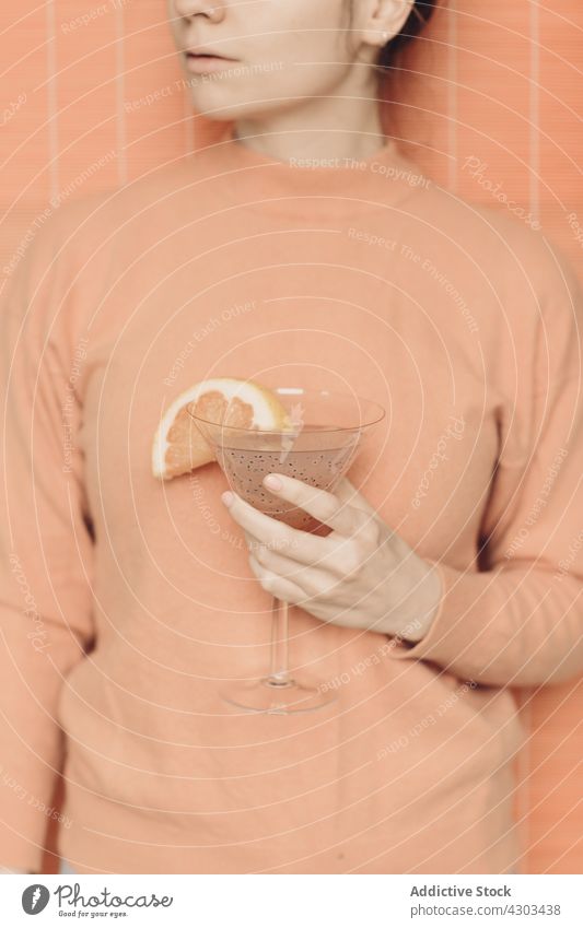 Crop-Frau mit Cocktail im Studio Martini sehr wenige Erfrischung trinken rosa Farbe Pastell Getränk Glas Scheibe Alkohol Frucht Grapefruit Garnierung lecker